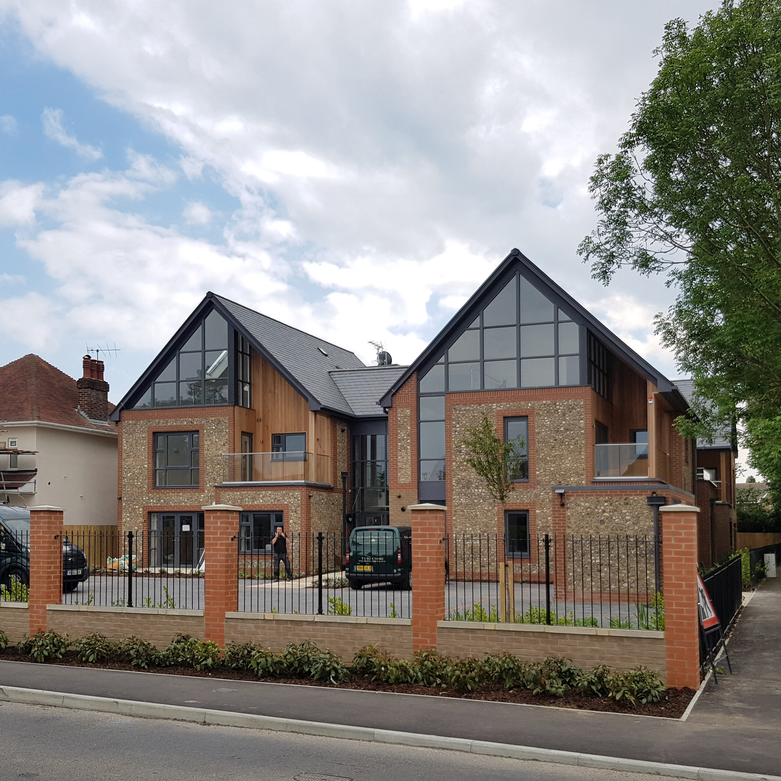A pair of glazed gables over contemporary brick and flint facades